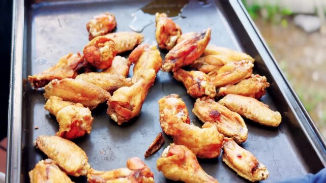 Cook Pours Fried Chicken Wings Onto Metal Tray