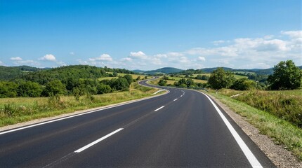Fototapeta premium Clear sky stretches above winding asphalt road. Fresh pavement gleams under bright daylight. Green hills roll gently on either side. White lines mark lanes inviting steady travel