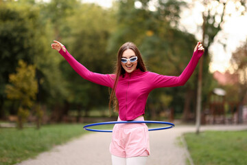 Athletic young woman exercising with hula hoop in park © New Africa
