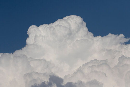 Cumulus congestus cloud with towering cauliflower-like growth, bright white edges, and a darker flat base, formed by strong upward air currents and capable of producing showers.
