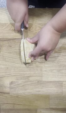 Top-down footage of a cook using a sharp stainless steel knife to finely slice and dice celeriac root on a wooden cutting board.