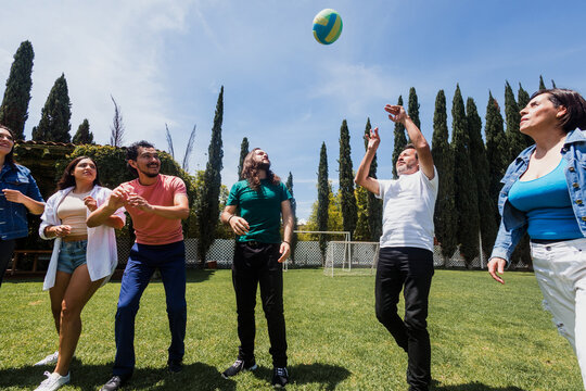 group of latin friends playing volleyball game in public park in Mexico Latin America. multicultural hispanic teamwork having fun together outdoors