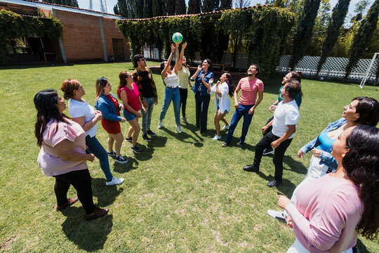 group of latin friends playing volleyball game in public park in Mexico Latin America. multicultural hispanic teamwork having fun together outdoors