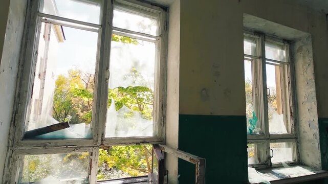 A broken window in a abandoned building with a run-down exterior
