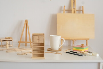 Tall miniature cabinet and easel with blank canvas on white table, assembly taking whole free evening, mood for craft content. Still life. Concept of assembly of dollhouse furniture at home © iwavephoto