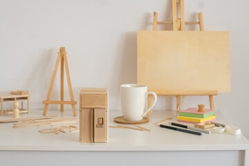 Miniature furniture and sticks near wooden easel and white cup, assembly that teaches real patience, hobby that needs real patience. Still life. Concept of assembly of dollhouse furniture at home © iwavephoto