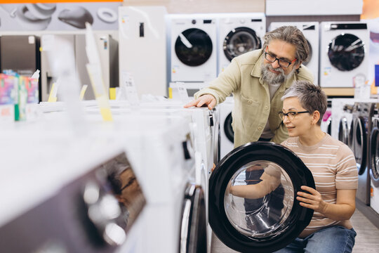 Mature couple shopping for a new washing machine in an appliance store, making a purchase decision