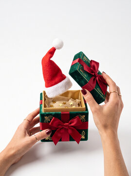 Hands opening a green Christmas gift box with Santa hat