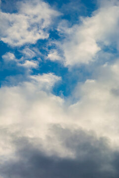 A dense gray cloudbank rises below scattered white cloud fragments 
