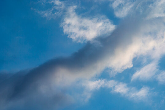 A long gray cloud ribbon crosses an opening of blue sky 