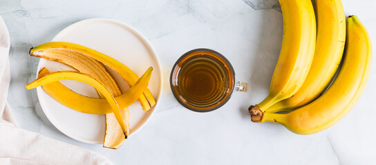 Evening sleep drink made from banana peel in a glass on the table top view web banner © elenarui