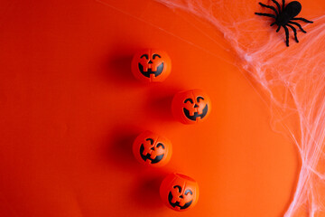 Fototapeta premium Top-down view of a Halloween background featuring pumpkin buckets and a spider on its web against an orange surface, with ample space for text