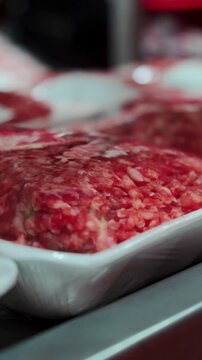 Fresh minced meat trays sit arranged neatly on refrigerated supermarket shelf. Clear plastic wrap covers raw ground beef portions, keeping perishable food items cold and protected inside store.