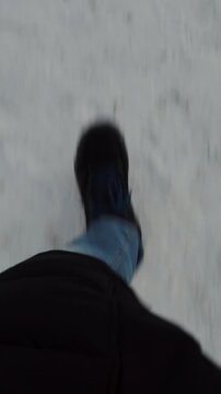 Individual strides across icy snow path while dressed in heavy winter clothing and dark boots. Moving traveler continues walking steadily through frozen outdoor environment with calm focus.