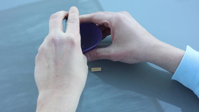 Male hands grinding marijuana buds with a herb grinder to prepare for rolling a joint