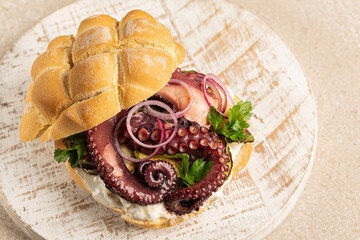 Tender octopus tentacles Seafood sandwich made with traditional italian tartaruga bread, filled with  stracciatella cheese, grilled zucchini,  and fresh parsley,  on a wooden board,  High angel view. © Olga