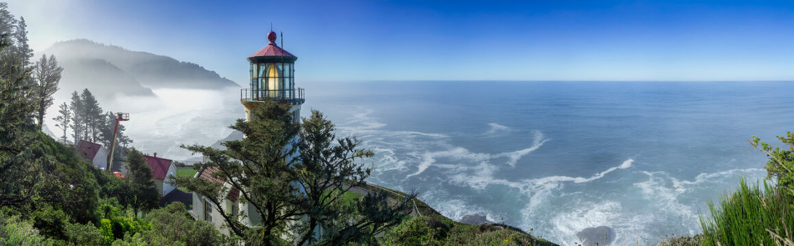 Beautiful wide panoramic view of a historic lighthouse on a misty rocky ocean coast at sunrise