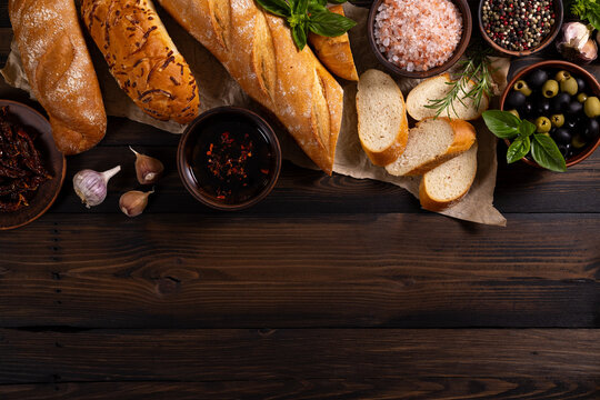 Fresh bread, olives, spices, and herbs on wood
