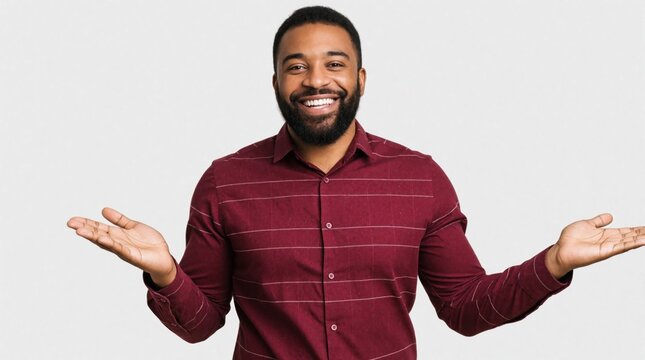 Smiling African American man in maroon shirt presents with open hands on white background. Happy black male person shows product information with friendly gesture. Confident young adult gesticulates