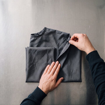 Two hands folding one dark cutting cape