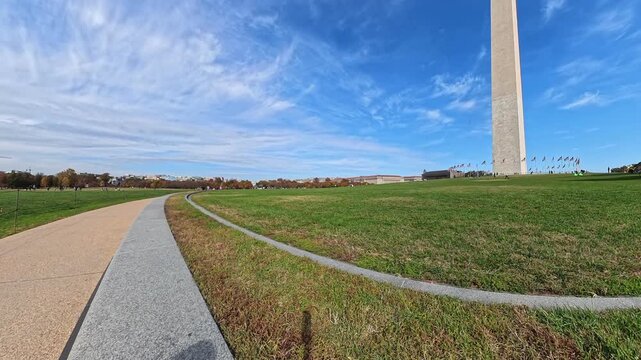  Rightward pan reveals Washington Monument beside a curving park pathway in 4K video.
