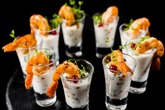 Shrimp cocktail appetizers in shot glasses on black background