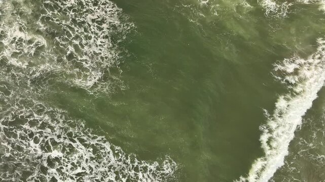 Aerial view of the Pacitan rip current showing turbulent green ocean water and white sea foam patterns in Pacitan, East Java, Indonesia.