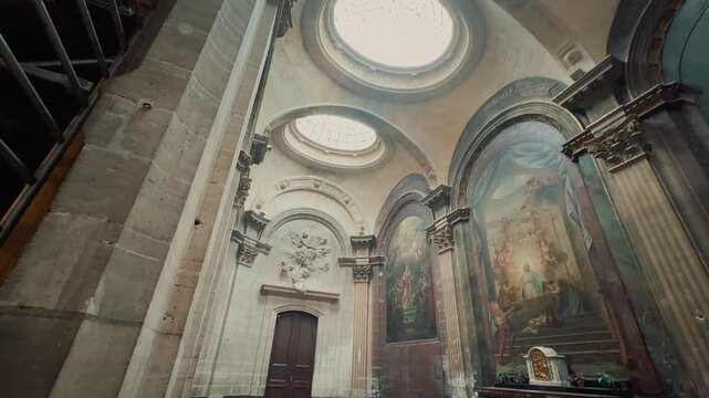 Explore the majestic interior of a historic French church, showcasing soaring Gothic ribbed vaults, colorful stained glass windows, serene altar with crucifix, and classical paintings in side chapels.