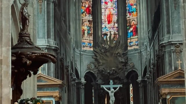 Explore the majestic interior of a historic French church, showcasing soaring Gothic ribbed vaults, colorful stained glass windows, serene altar with crucifix, and classical paintings in side chapels.