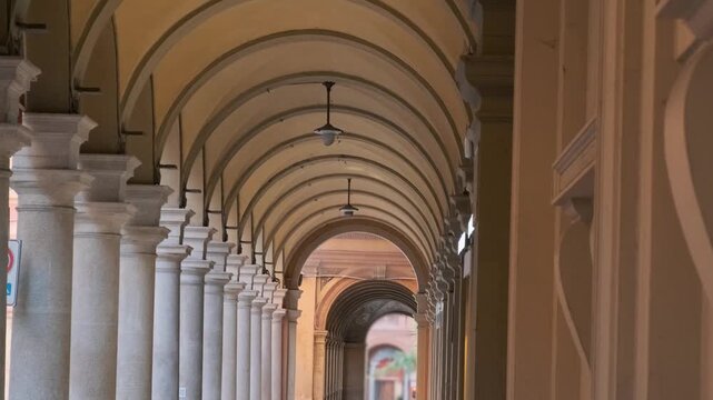 Historic portico with rows of columns and repeating arches in Bologna old town, Emilia-Romagna, Italy. Pedestrian architecture, colonnade perspective, traditional Italian urban design