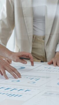 Business team analyzing financial charts and graphs, pointing at statistics and discussing data, working together on business project in modern office, close up. Business people concept
