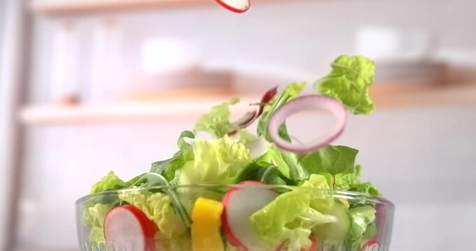 Fresh vegetable salad falling into glass bowl kitchen background slow motion 1000 fps