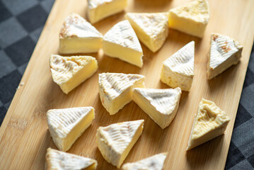 Camembert cheese cut into triangles on a wooden cutting board on a dark background © Konstiantyn Zap