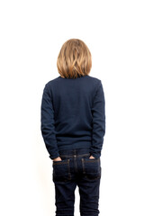 Positioned against a clean slate, a young boy with long hair stands in reverse, creating a simple yet elegant composition © Konstiantyn Zap