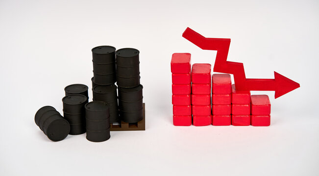Oil barrels beside a descending block chart and downward arrow isolated on white background.
