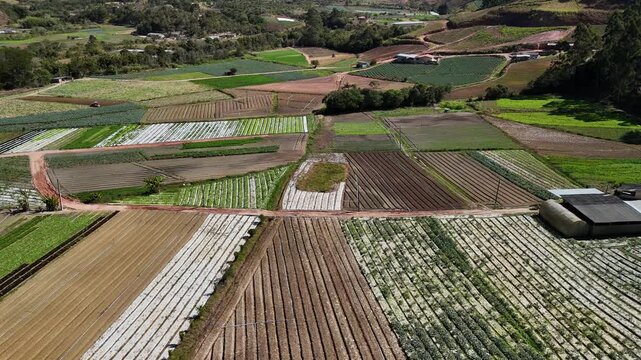 Aerial view of the Tres Picos de Friburgo mountain range overlooking lush green agricultural fields and rural farmland in Nova Friburgo, Rio de Janeiro, Brazil.