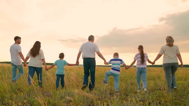 Happy family, walk in meadow. Dad mom, children walking outdoors. Family picnic in nature. Parents father mother, kids daughter son walk together grass, holding hands. Unity people. Vacation holiday