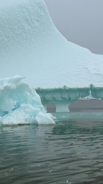 Vertical Video of Scattered Icebergs Across Turquoise Water. White and blue ice, rippling water and soft diffuse light reveal natural frozen texture and sculpted contours across the marine scene.