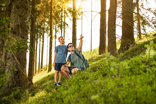 Father teaching his son about nature while hiking together in a forest during an outdoor family adventure