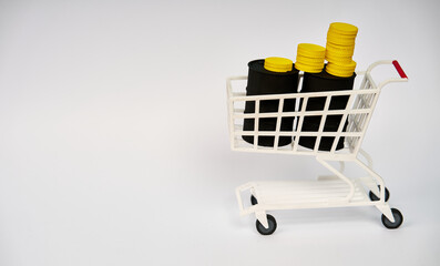 Shopping cart filled with oil barrels and stacked coins representing energy spending and rising consumer costs isolated on white background  © kaliel