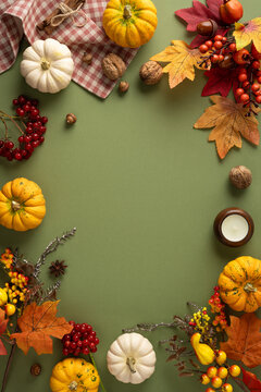 Autumn Thanksgiving vertical flat lay with pumpkin, colorful leaf, berry and harvest decoration on soft green background for festive celebration