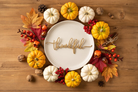 Autumn thankful plate with mini pumpkins, maple leaves and berries for Thanksgiving table