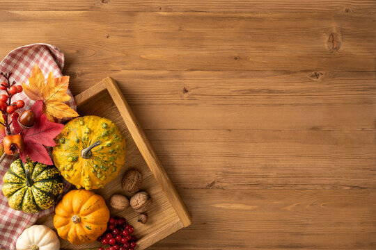 Autumn thanksgiving table with decorative gourds, pumpkins, walnuts and fall leaves on wooden board with space for advert