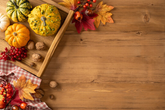 Autumn Thanksgiving flat lay with pumpkins, gourds, fall leaves and walnuts on wooden table with tray