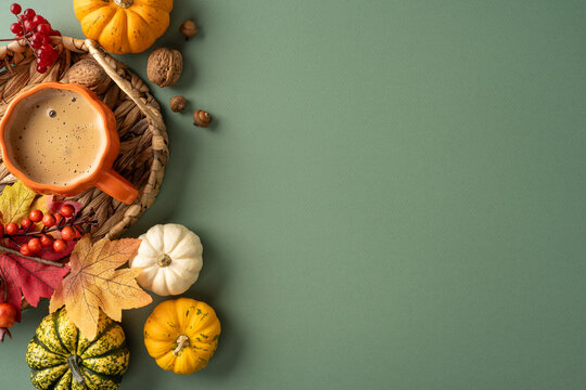 Autumn coffee with small pumpkins, fall leaves and nuts on green background for Thanksgiving with empty place for text and promo