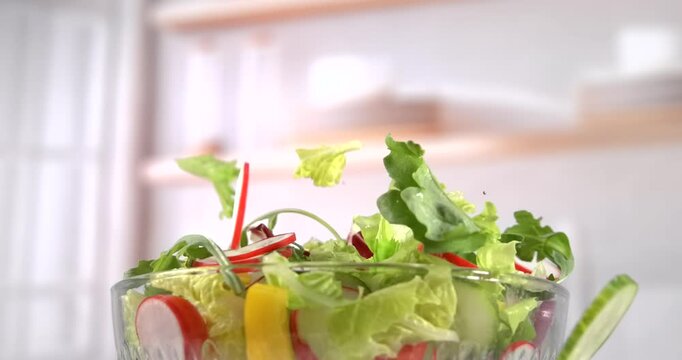 Fresh vegetable salad falling into glass bowl kitchen background slow motion 1000 fps