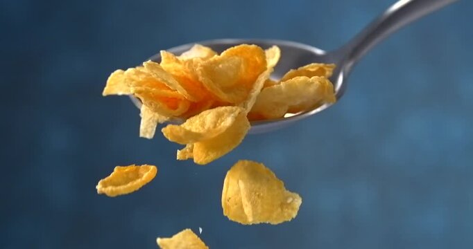 Corn flakes falling from a spoon in slow motion on blue background