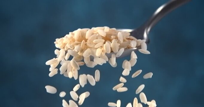 Rice grains falling from a spoon in slow motion on blue background
