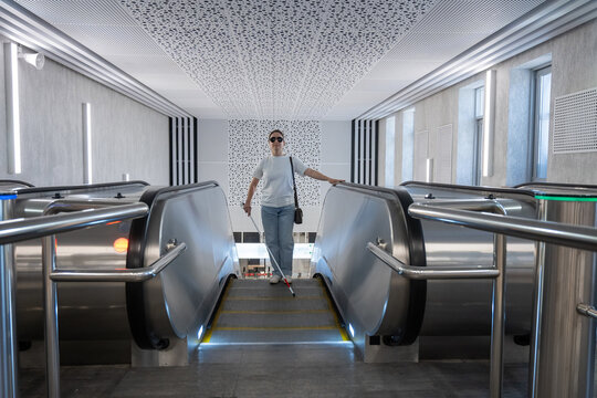 A blind woman rides an escalator in the subway.