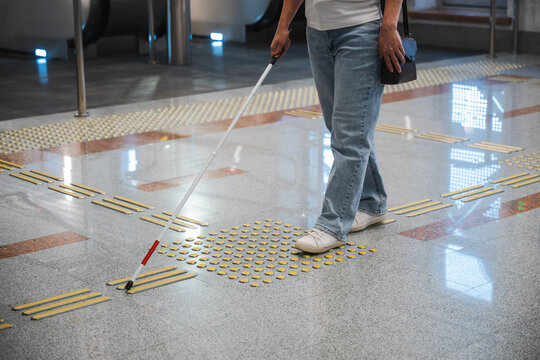 A blind woman in the metro near an escalator follows tactile navigation tiles.